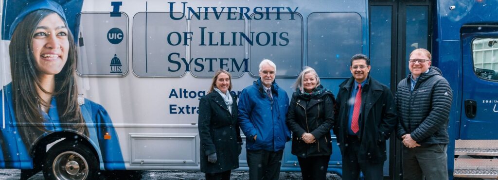 5 adults in front of UI Ride Shuttle bus