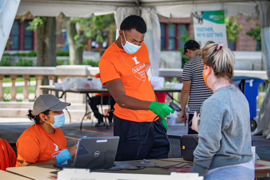 student scanning another student I-card at COVID-19 testing tent