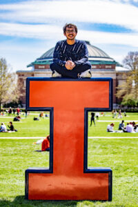 student atop an orange block I on the main quad