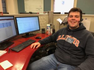 Sam, Help Desk Team Lead, sits by his computer with a headset and a smile.