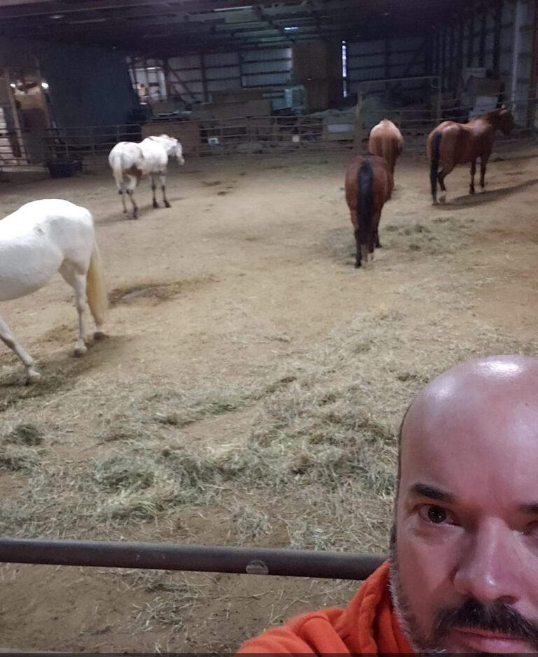 Close-up image of Shawn standing by a horse farm, showing where he takes care of horses now.